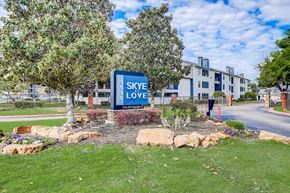 Dallas apartment for rent - a blue sign that says sky love in the middle of a grassy area with trees and