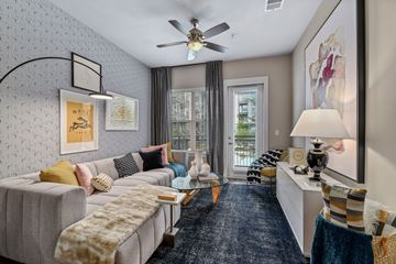 Dallas apartment for rent - A living room with a grey couch and a ceiling fan.