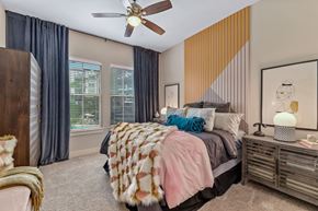 Dallas apartment for rent - A bedroom with a bed, a ceiling fan, and a window with curtains.