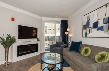 Warrenville apartment for rent - A living room with a grey couch, a glass table, a fireplace, and a painting on the wall.