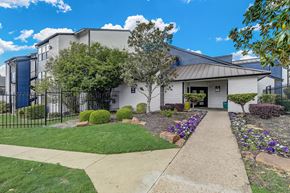 Dallas apartment for rent - a white building with a gray roof and a sidewalk leading to the front door
