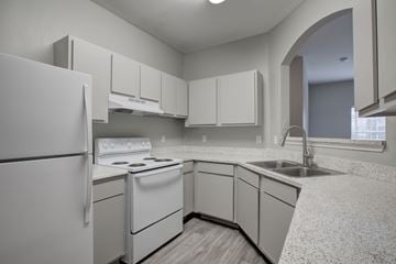 Houston apartment for rent - A white kitchen with a refrigerator, stove, and sink.