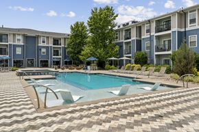 Lone Tree apartment for rent - A swimming pool surrounded by a tiled patio and lounge chairs in front of apartment buildings.
