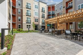 Warrenville apartment for rent - A patio area with a table and chairs is surrounded by apartment buildings.