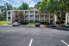 Gastonia apartment for rent - a parking lot with cars in front of an apartment building