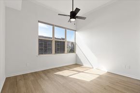 Dallas apartment for rent - A room with a ceiling fan and a window overlooking a building.