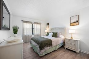 Stuart apartment for rent - A bedroom with a bed, nightstand, and a plant on the dresser.