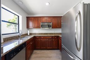 Stuart apartment for rent - A kitchen with wooden cabinets and a stainless steel refrigerator.