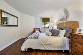 Sunrise apartment for rent - A bedroom with a large bed and a wicker headboard.