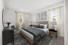 Lake Worth apartment for rent - A bedroom with a large bed, a side table with a lamp, and a dresser with a mirror.