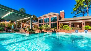 Houston apartment for rent - A large swimming pool in front of a house with a covered patio area.