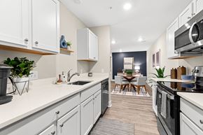 Howell townhouse for rent - an open kitchen with white cabinets and appliances and a living room with a dining room
