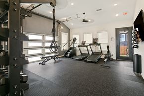 Fort Worth apartment for rent - A gym with a variety of equipment including treadmills, weights, and a TRX suspension trainer.
