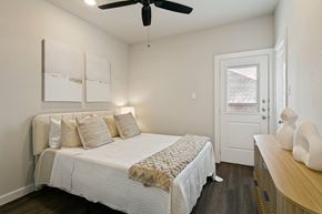 Fort Worth apartment for rent - A bedroom with a bed, a ceiling fan, and a wooden dresser.