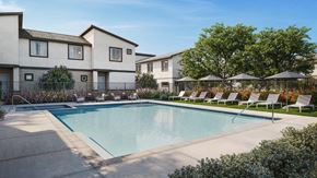 Phoenix apartment for rent - A swimming pool is surrounded by lounge chairs and umbrellas in front of apartment buildings.