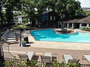 Houston apartment for rent - A pool surrounded by chairs and trees.