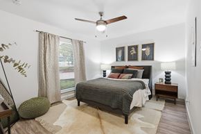 Fort Worth apartment for rent - A bedroom with a bed, a ceiling fan, and a rug.