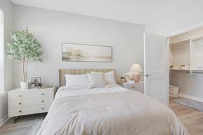Skokie townhouse for rent - A white bedroom with a large bed, a nightstand with a lamp, and a painting on the wall.
