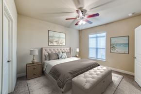 Waco apartment for rent - A bedroom with a large bed, a ceiling fan, and two pictures on the wall.
