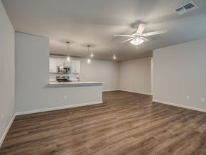 Oklahoma City triplex for rent - an empty living room with a ceiling fan and a kitchen in the background