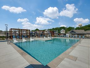 Anna apartment for rent - A large swimming pool with a blue tinted water and white chairs around it.