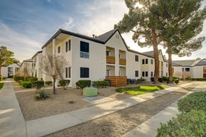 Henderson apartment for rent - a street view of a white apartment complex with a tree in the foreground