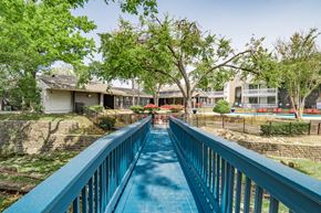 Dallas apartment for rent - a blue bridge over a swimming pool with houses in the background