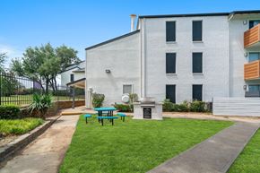 Dallas apartment for rent - a patio with a grill and picnic table in front of a white building