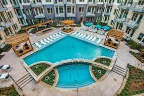 Farmers Branch apartment for rent - A large outdoor swimming pool surrounded by a patio area with chairs and umbrellas.