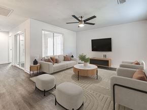 Oklahoma City apartment for rent - A living room with a white couch, a wooden coffee table, and a flat-screen TV mounted on the wall.