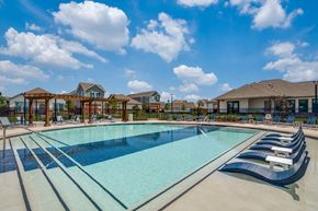 Lavon apartment for rent - A large outdoor swimming pool with loungers and a clear blue sky.