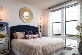 Houston apartment for rent - A bedroom with a large bed and a round mirror on the wall.
