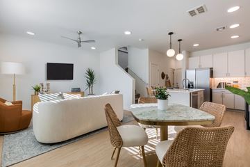 Albuquerque apartment for rent - A modern living room with a white sofa, a TV, and a dining table with chairs.