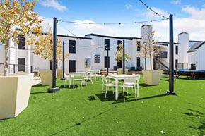 Dallas apartment for rent - a courtyard with tables and chairs and a building in the background