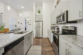 Mckinney apartment for rent - Bright apartment kitchen view featuring stainless steel appliances integrated with light cabinetry and dark floors.