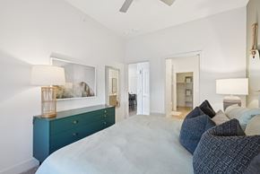 Plano apartment for rent - A bedroom with a large bed and a dresser with a lamp on top.