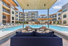 Austin townhouse for rent - A large blue couch is in the foreground of a pool area with a wooden ceiling.