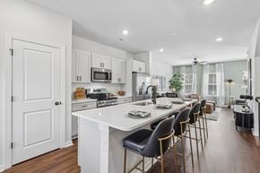 Charlotte townhouse for rent - A modern kitchen with white cabinets and a long island with chairs.