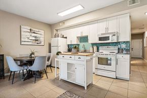 Panama City Beach apartment for rent - A kitchen with white appliances and a dining table with chairs.