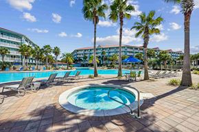 Panama City Beach apartment for rent - A pool surrounded by palm trees and lounge chairs.