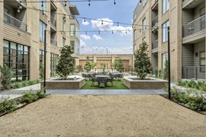 Dallas apartment for rent - A courtyard surrounded by buildings with a table and chairs in the middle.