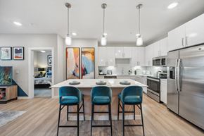 Brighton apartment for rent - a kitchen with stainless steel appliances and an island with blue chairs