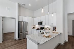 Katy apartment for rent - A modern kitchen with a stainless steel refrigerator and a marble countertop.