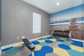 Dallas apartment for rent - a workout room with a gym bench and a wall mural of the beach