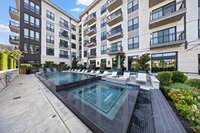 Dallas apartment for rent - A large outdoor pool surrounded by lounge chairs and buildings.