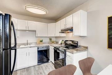 Aurora apartment for rent - A kitchen with white cabinets and a black fridge.