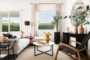 Prescott Valley apartment for rent - A living room with a white sofa, a coffee table, a chair, and a round mirror on the wall.