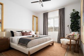Surprise apartment for rent - a bedroom with a bed and a plant and a ceiling fan