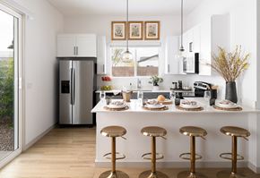 Surprise apartment for rent - a kitchen with a island with stools and a stainless steel refrigerator