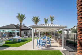 Prescott Valley apartment for rent - A white gazebo with blue chairs is surrounded by a lawn and palm trees.